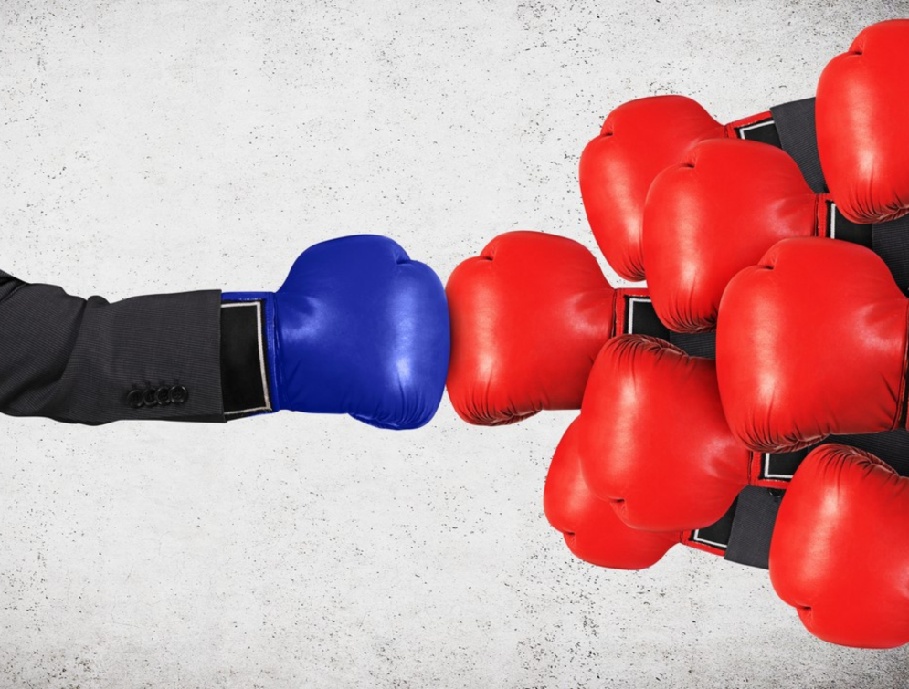 Person with boxing glove on punching several opponents.